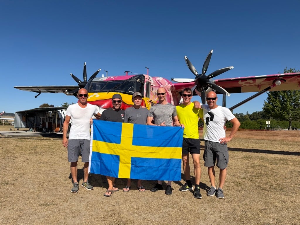 Svenska deltagare framför flygplan med svensk flagga